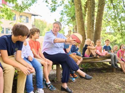 Schulgruppe mit Lehrerin und Ball draußen