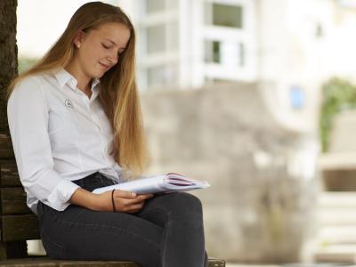 Landheim-Ammersee, Mädchen auf Bank an Baum sitzend und lernend