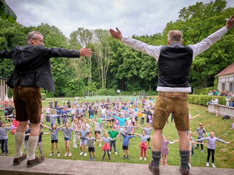 Schülergruppe die von zwei Männern zum sporteln angeleitet werden