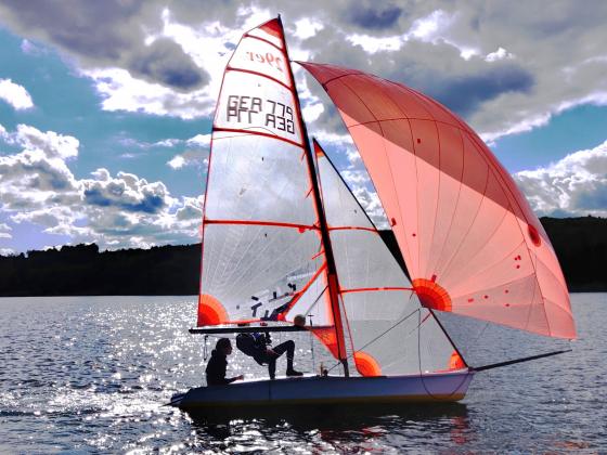 Segelboot unter vollen Segeln im Gegenlicht